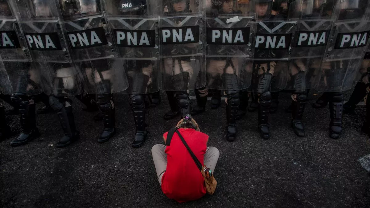 Una mujer intenta impedir la acción represiva de la Prefectura Nacional luego de que la Cámara de Diputados aprobara la Ley de Bases.
