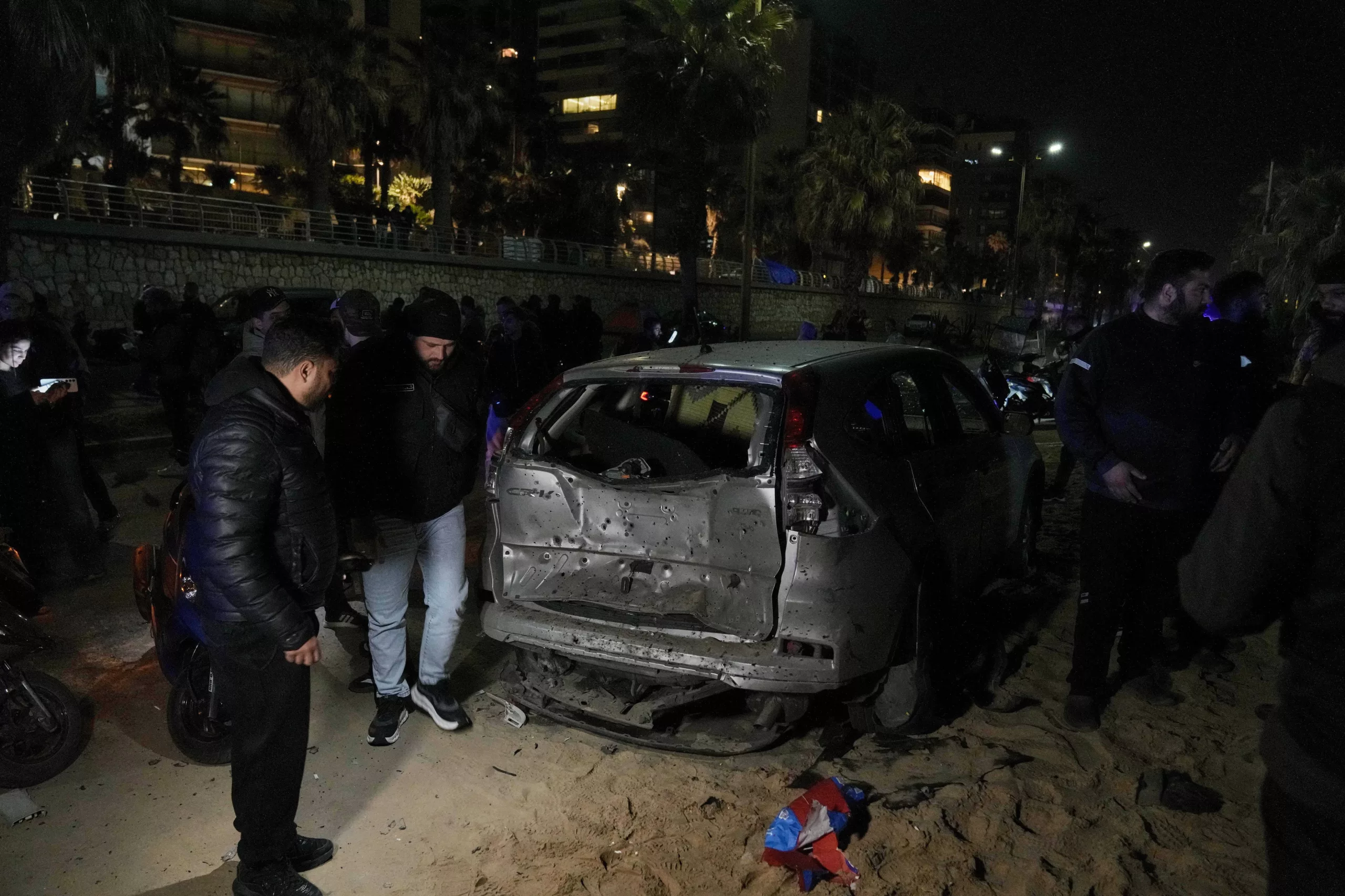 Personas se reúnen cerca de un automóvil dañado por un ataque aéreo israelí en la playa pública de Ramlet al-Baida, en Beirut, Líbano, la madrugada del jueves 12 de marzo de 2026. (Foto AP/Bilal Hussein)