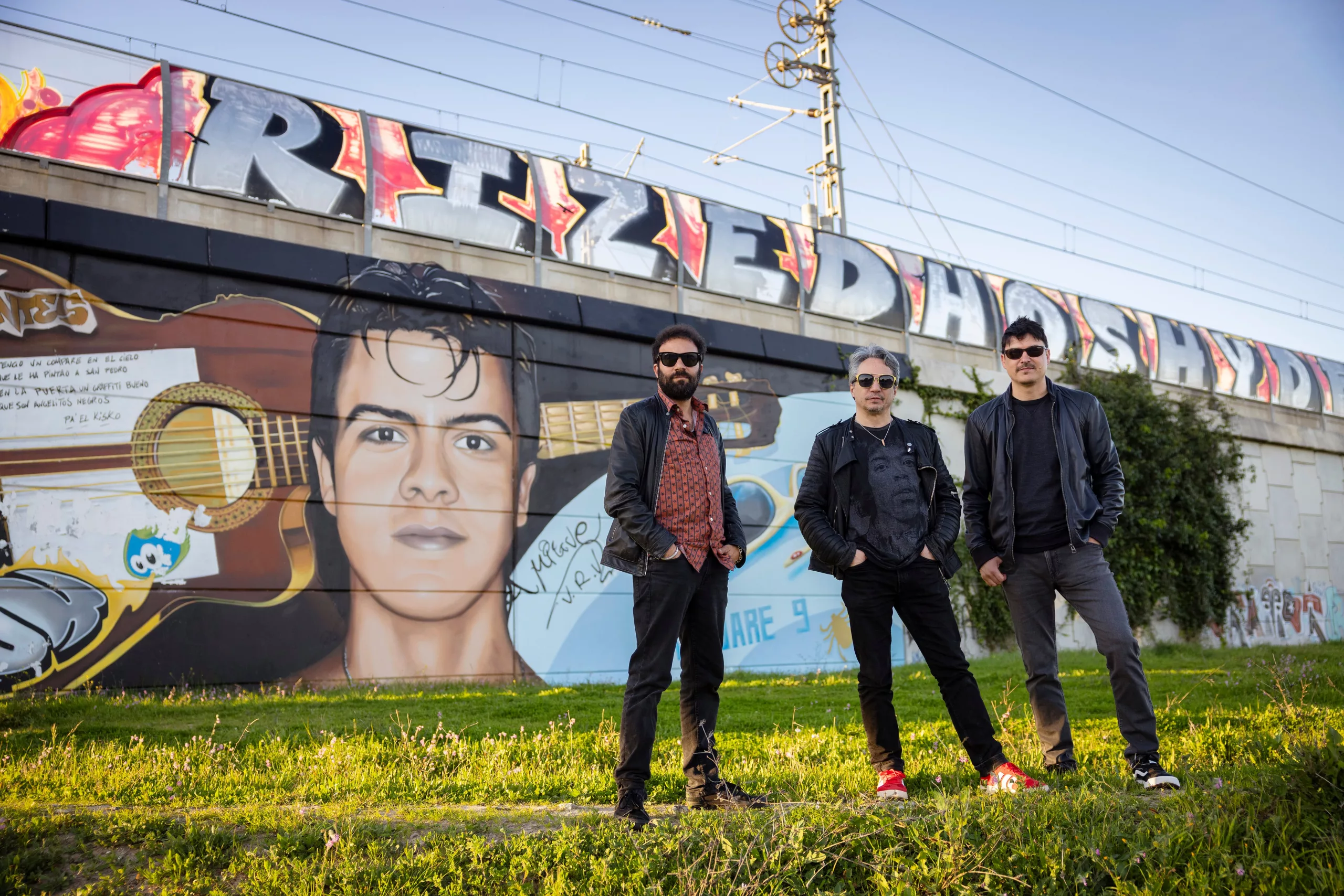 Desde la izquierda, Canijo de Jerez, Diego 'El Ratón' y Manu Benítez, hermano de Migue, que les mira desde un grafiti en el barrio de San José Obrero de Jerez.